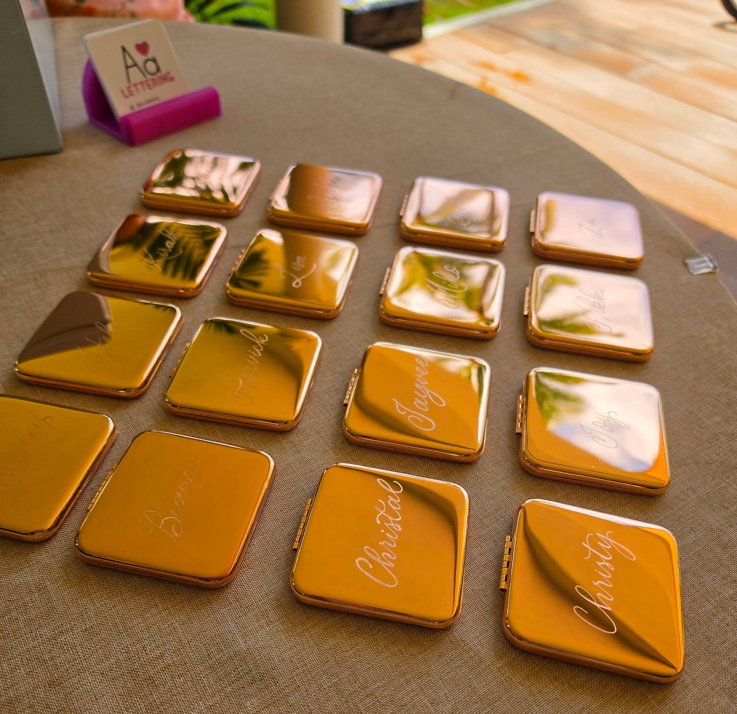 Rose gold compact mirrors with engraved names on a table